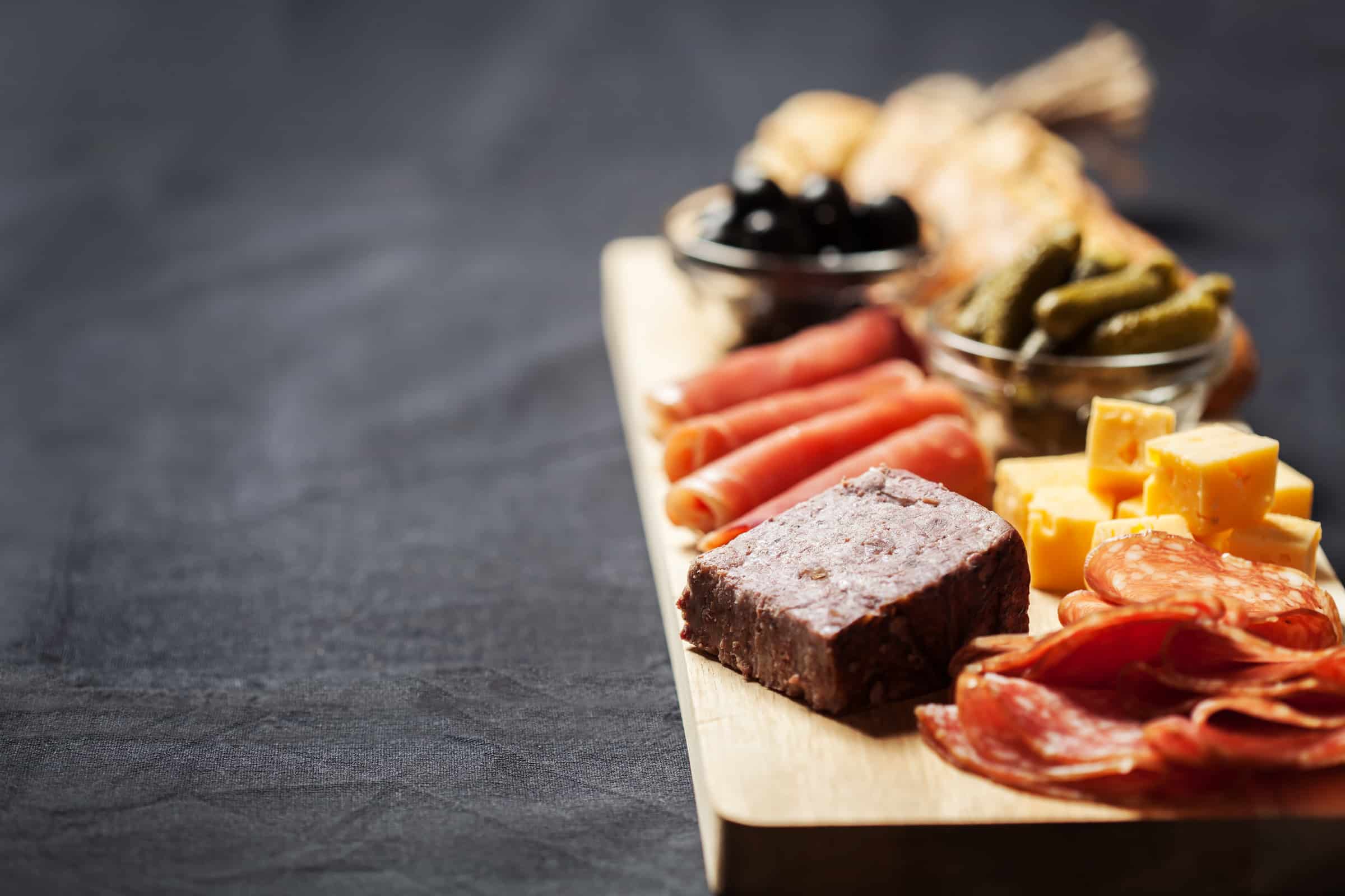 Charcuterie assortment, cheese, olives and gherkins on wooden board
