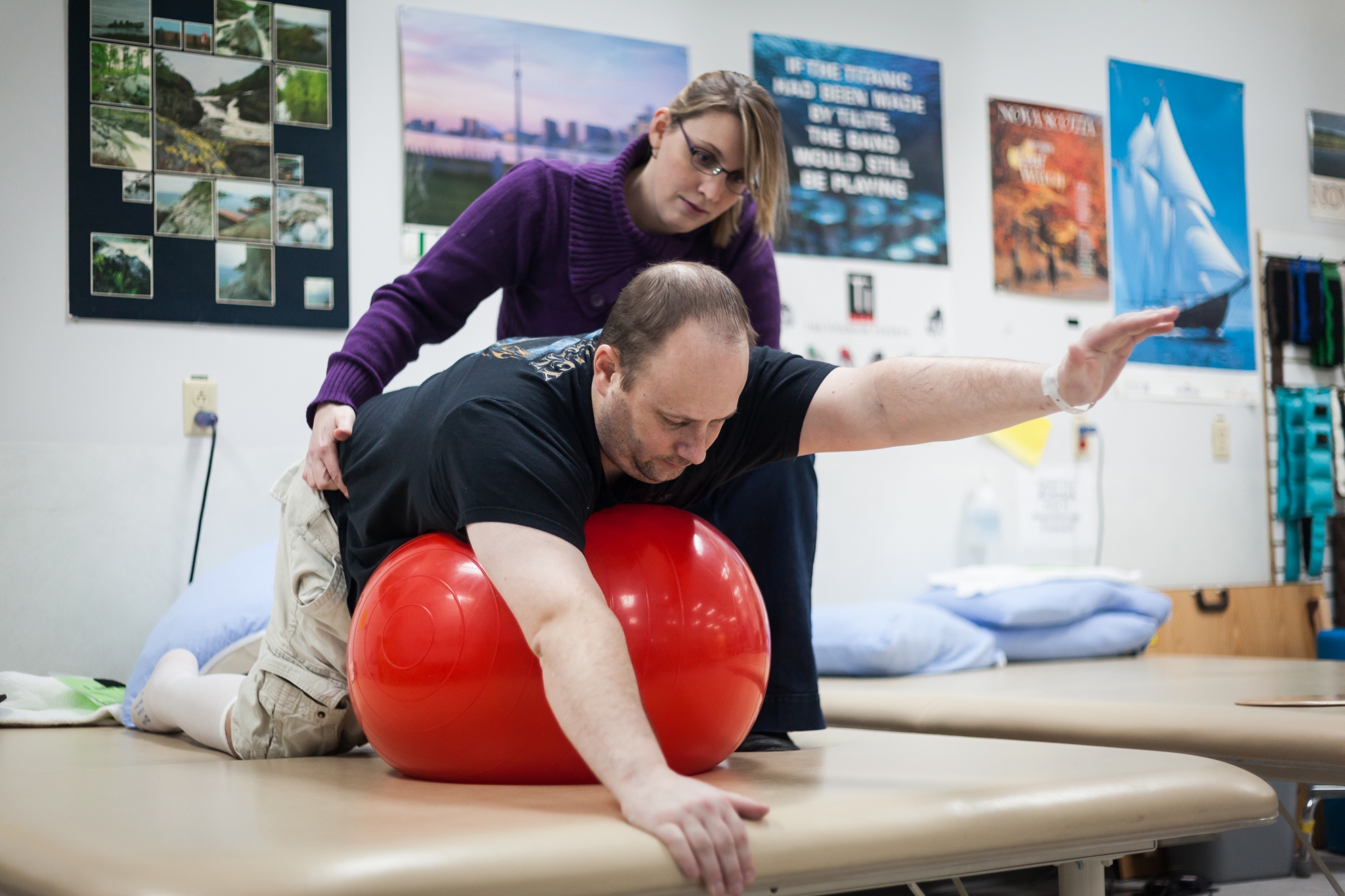 Physio-KS Physiotherapist working with adult patient on mobility exercises using large exercise ball.